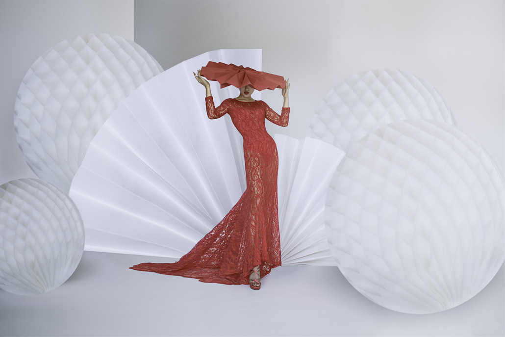 ﻿Woman in pink lace dress and large hat posing with white background